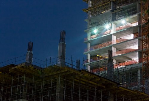 Construction site at night with lights against the dark sky
