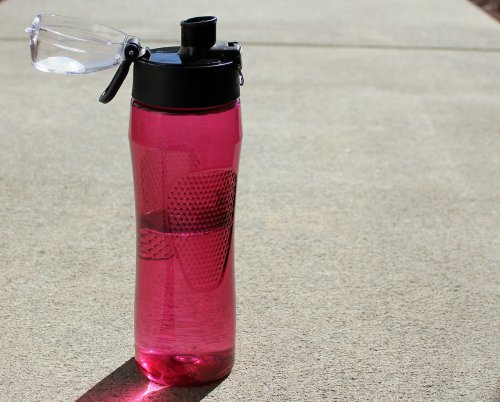 a pink reusable water bottle on the ground
