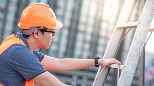 man holding onto ladder in a construction site
