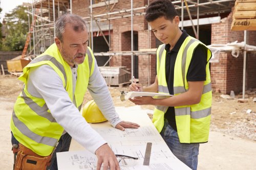 Scaffolder On Building Site Discussing Work With Apprentice